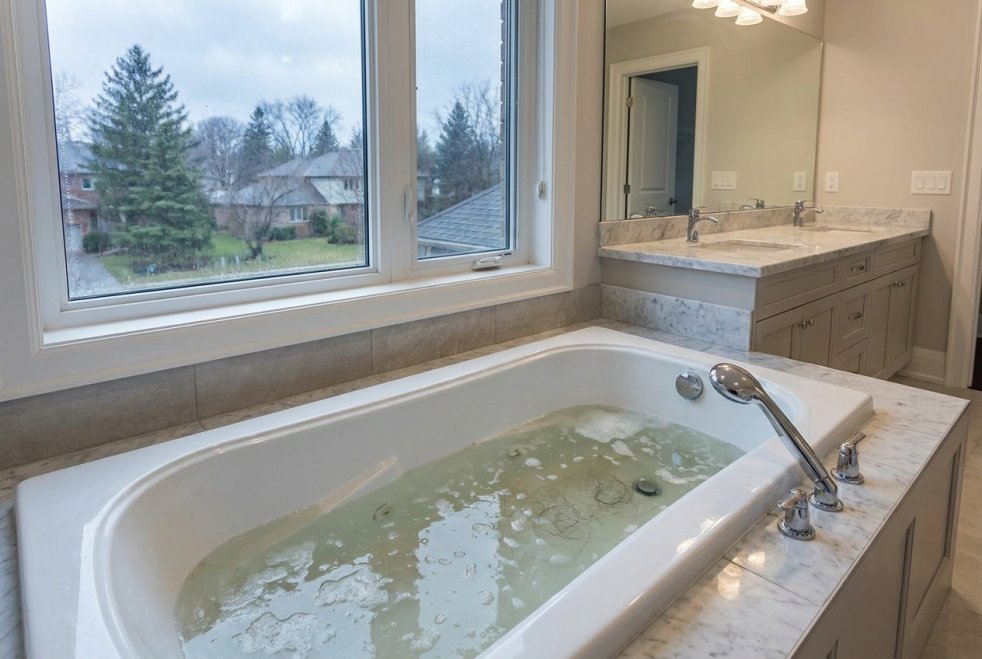 Clogged bathtub drain with standing water in a Chicagoland home bathroom